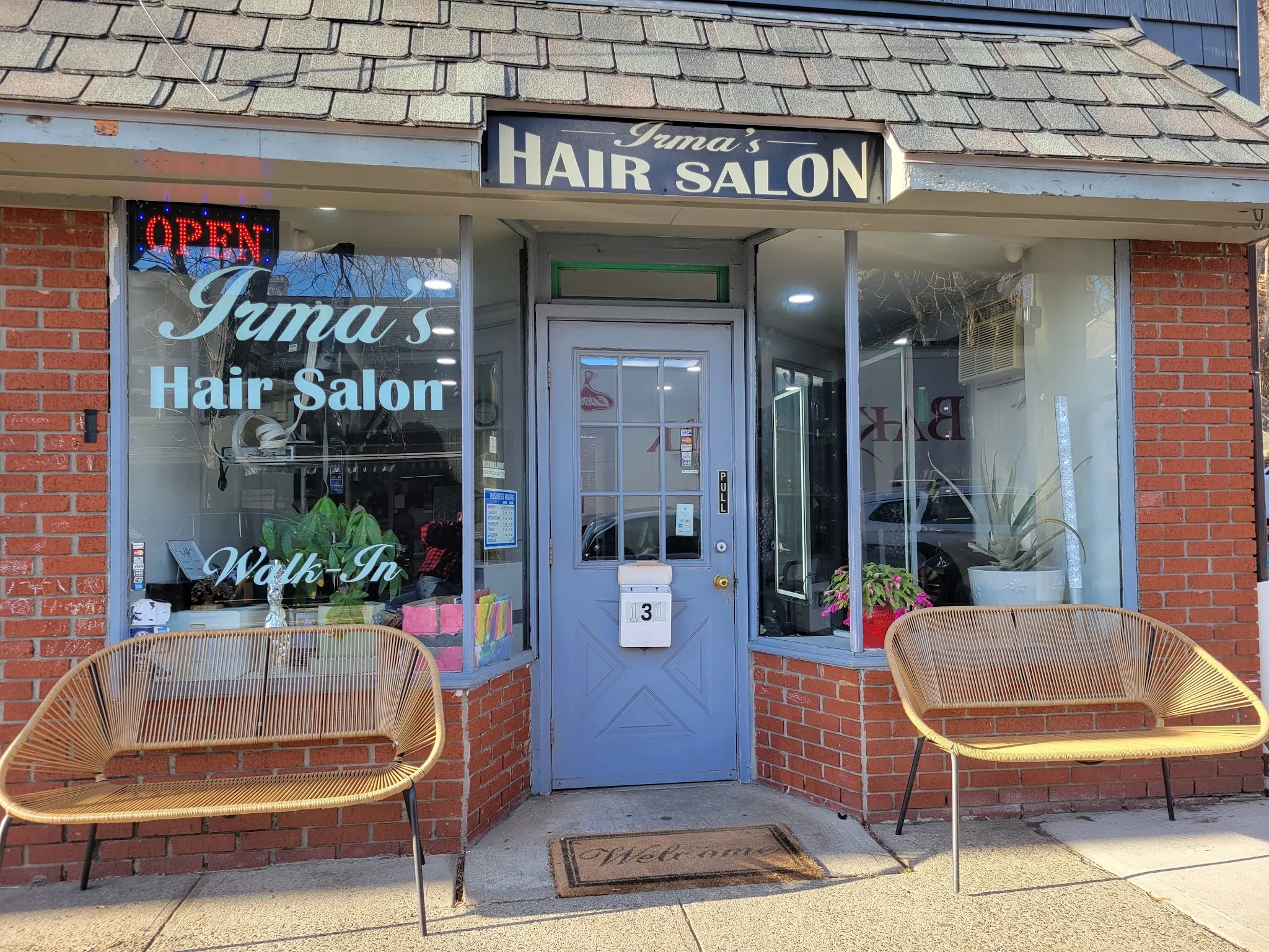 The front window, lettered Irma's Hair Salon and Walk-In, between two rattan benches