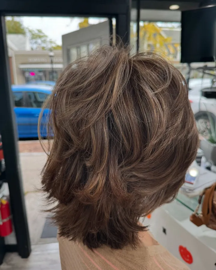 A feathered, layered shag in brown with lighter pieces, seen from the back
