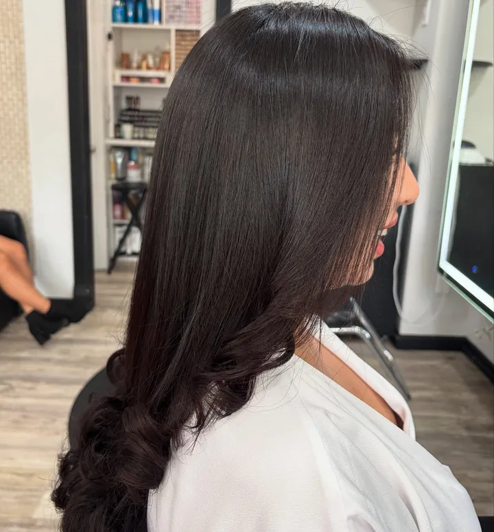 Long, glossy dark brown hair set with big curls at the ends